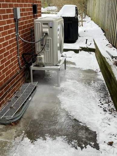 Heat pump outdoor unit coated in ice during a Greensboro NC cold snap